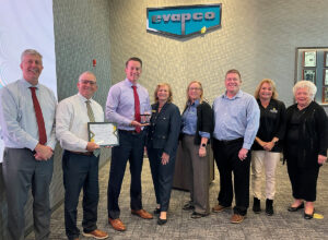 Image of Denise Beaver, ED Director presenting the Pillar Award to Jeff Poczekaj, VP Chief People Officer; Bill Jones, Sr. VP Global Operations; Patrick Strine, Jr., President & COO.