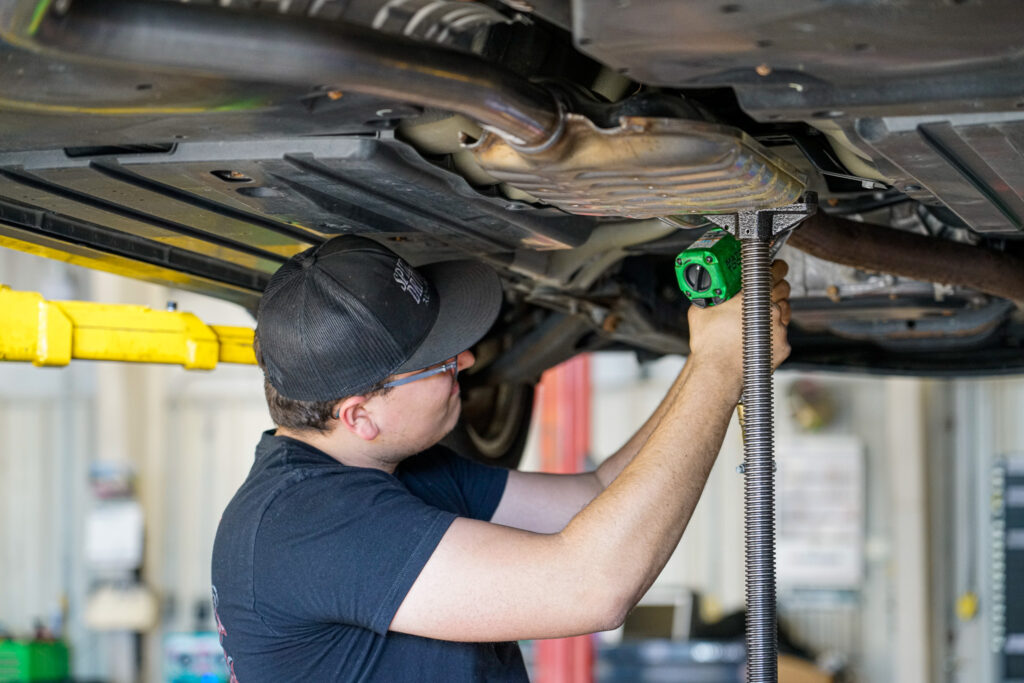 Image of an auto mechanic working on a vehicle that is on a lift